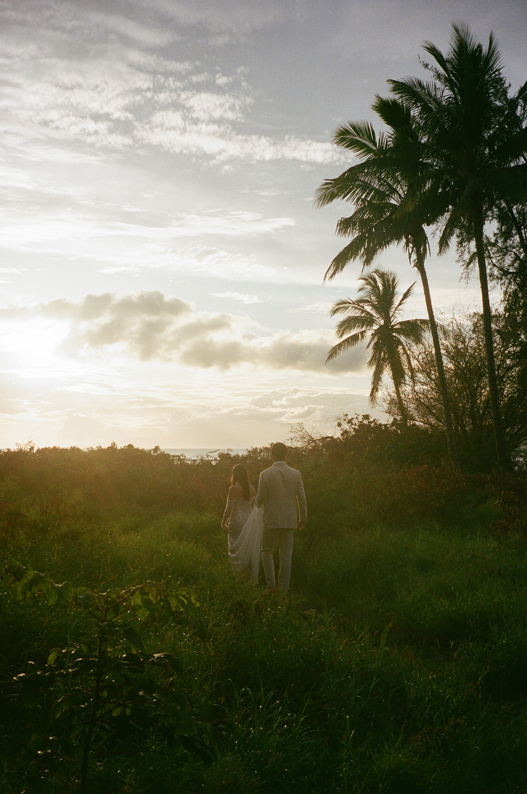 Silhouette of bride and groom walking toward the sunset during their Maui elopement
