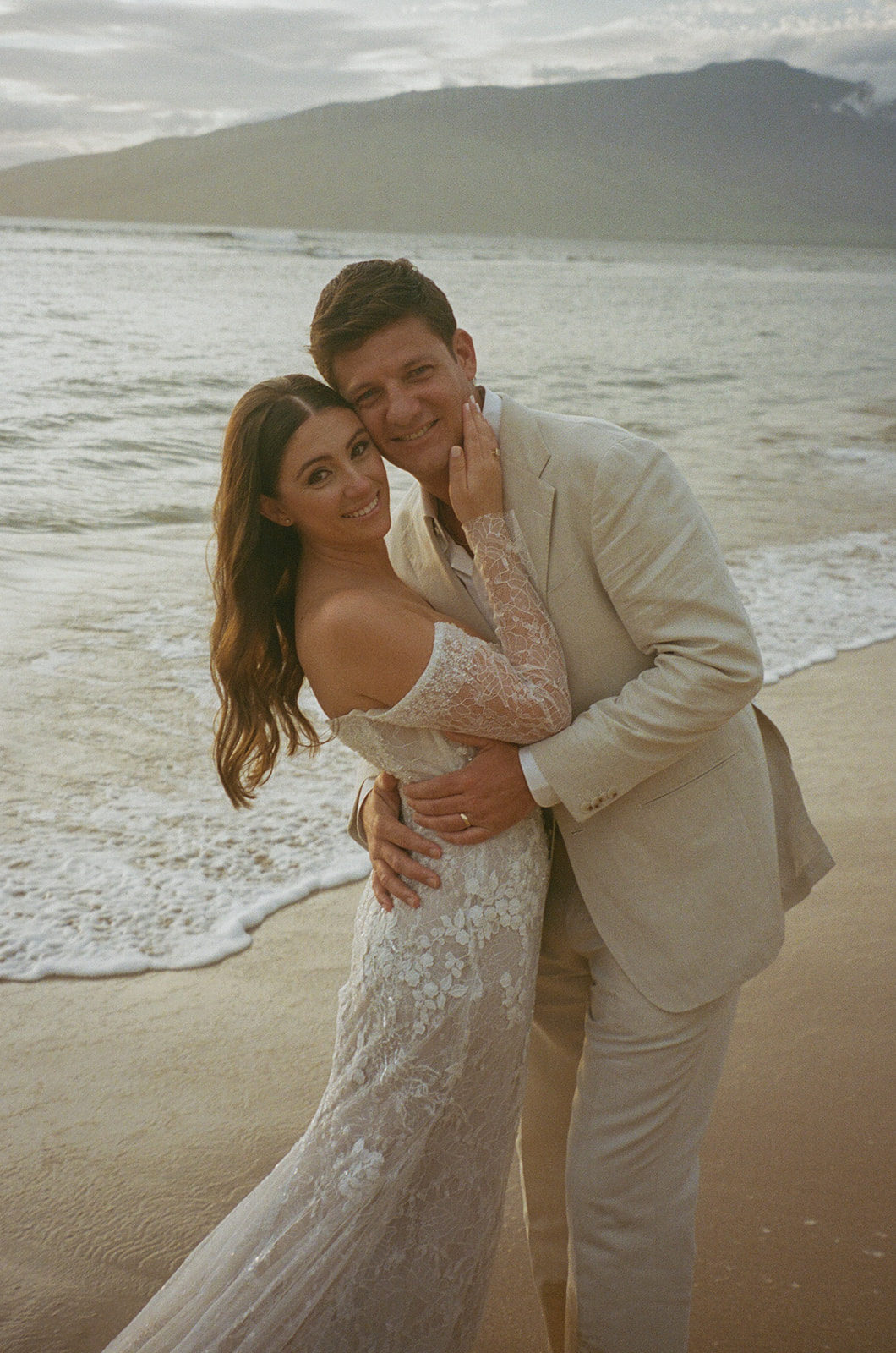 Bride and groom smiling and embracing on the beach during their Maui elopement
