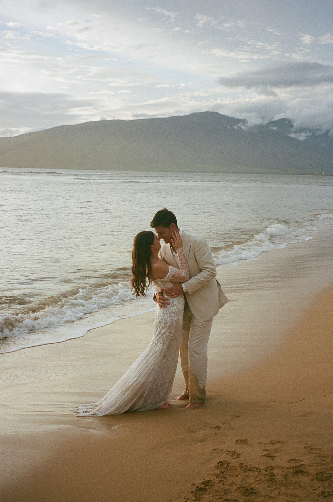 Bride and groom embracing at the shoreline during their Maui elopement at sunset
