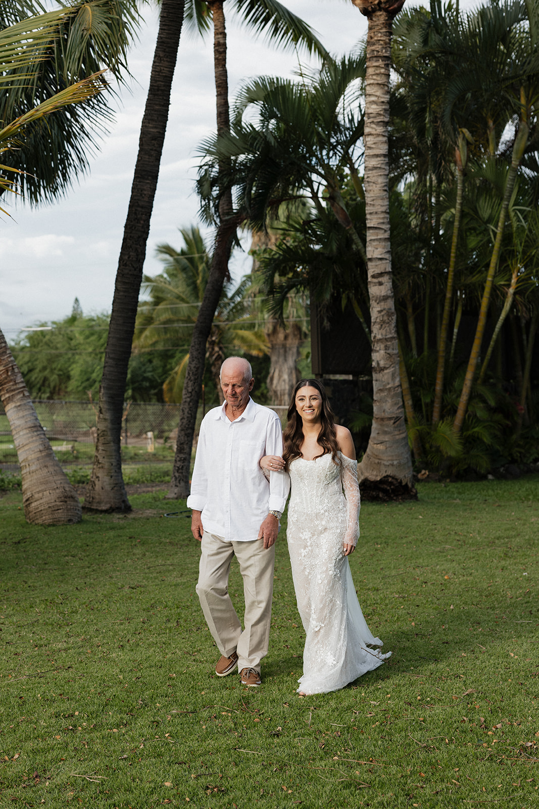 Father walking bride down the aisle surrounded by family and guests at a Hawaii wedding
