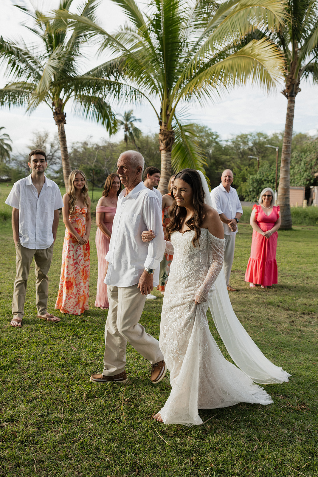 Father of the bride walking her toward the ceremony at their Maui elopement under palm trees
