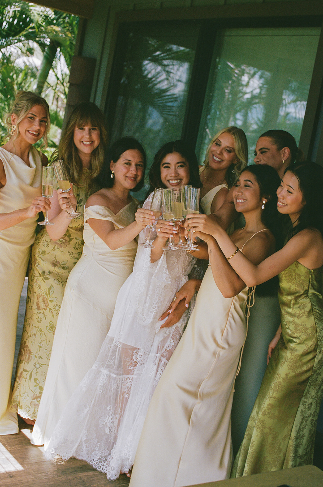 Bridesmaids and bride toasting with champagne flutes on a shaded lanai
