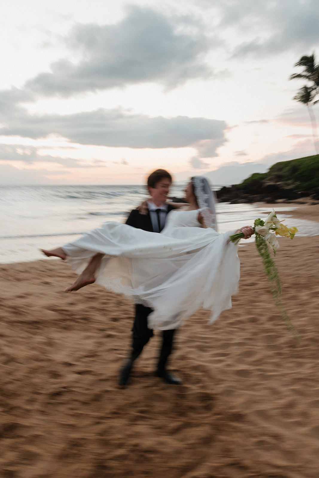 Wedding film photography motion shot of the groom twirling his bride on the sandy beach
