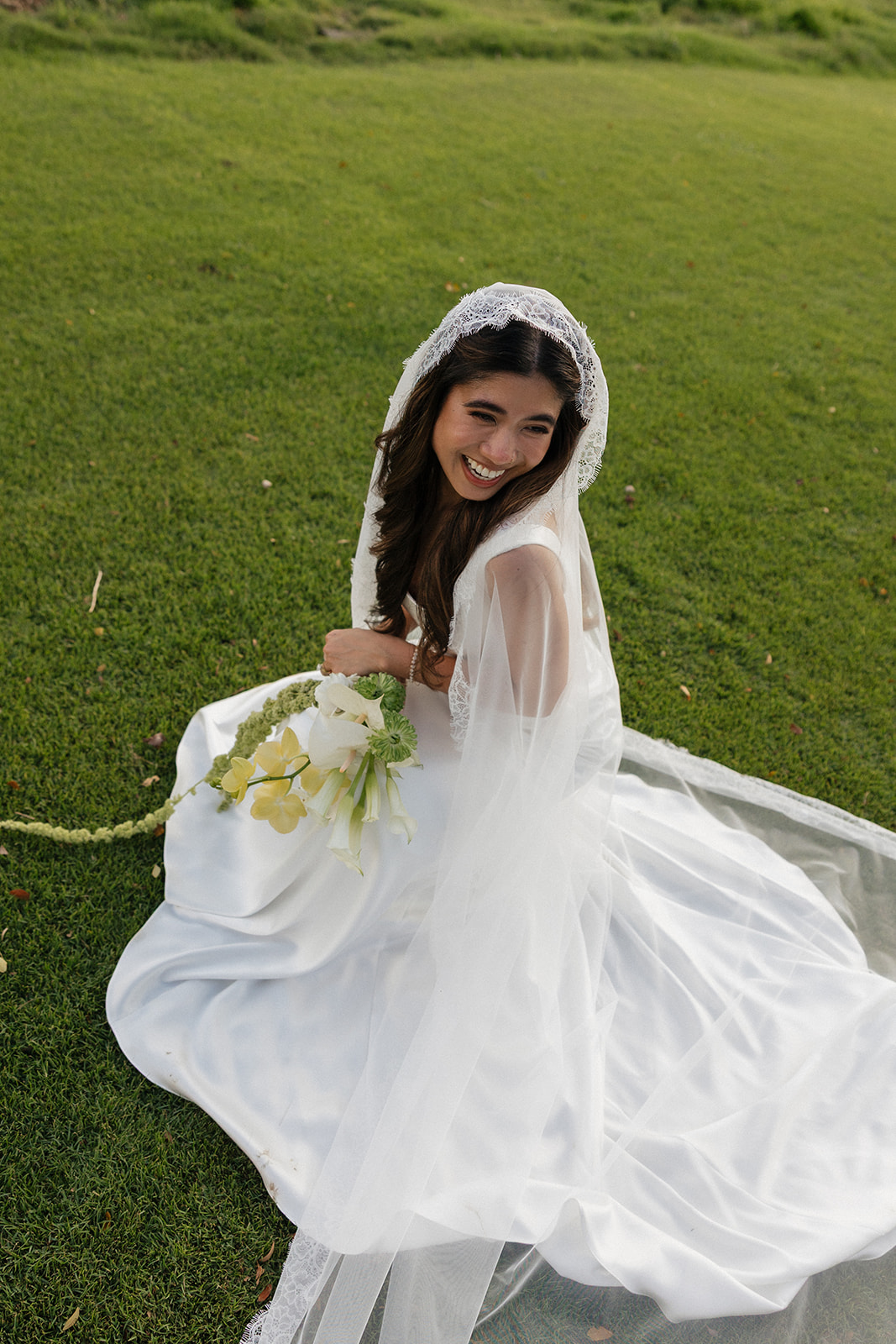 Wedding film photography of the bride twirling her gown and laughing on the grass