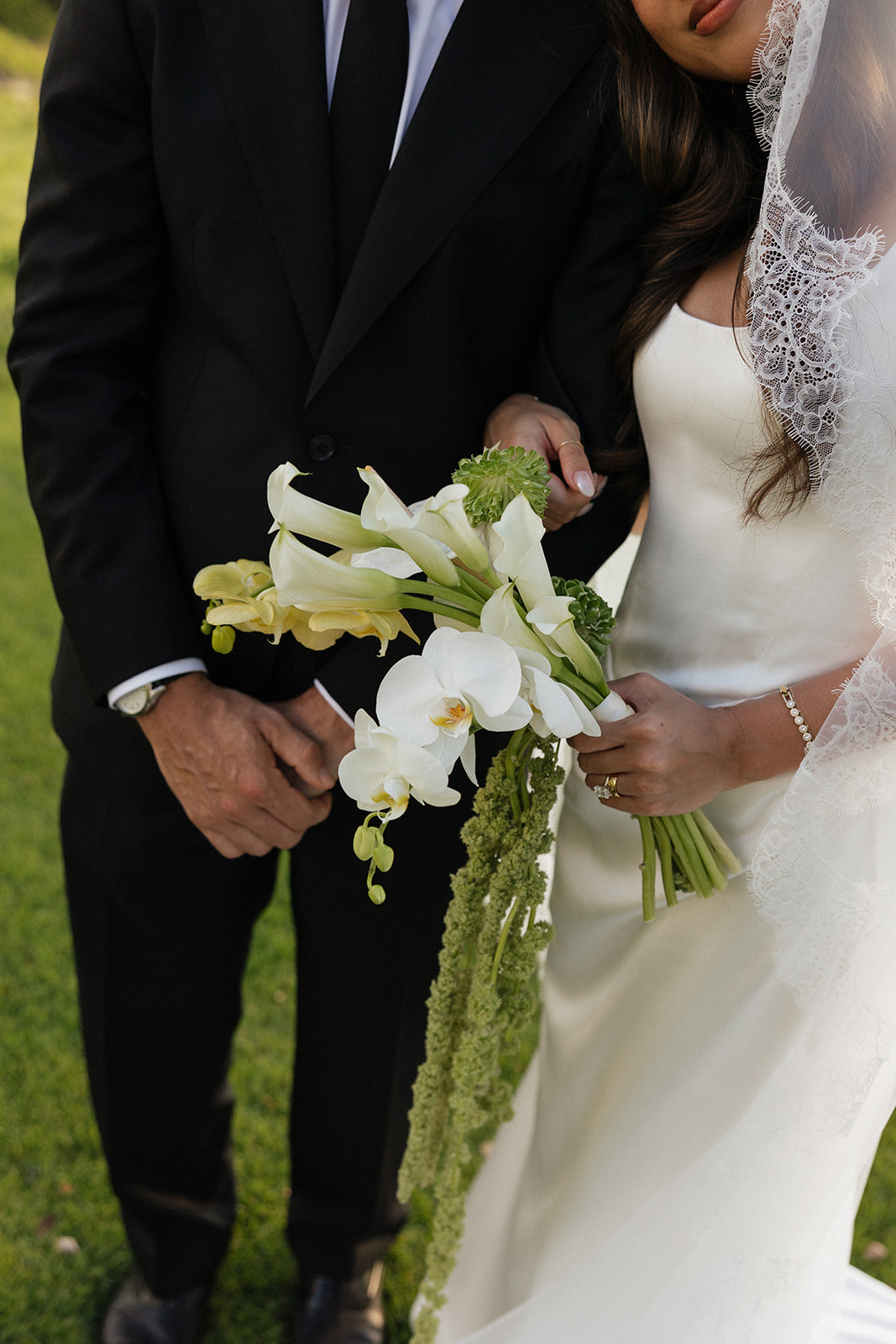 Wedding film photography close-up of the bride and groom holding their calla lily and orchid bouquet