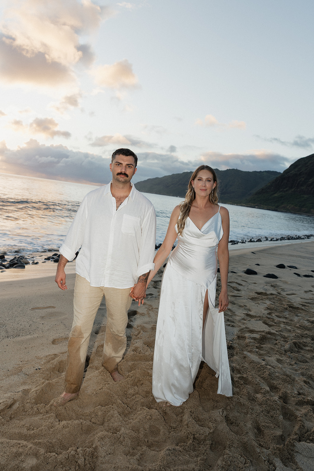 Bride and groom standing together on the beach, still a little wet from their beach elopement dip in the ocean.
