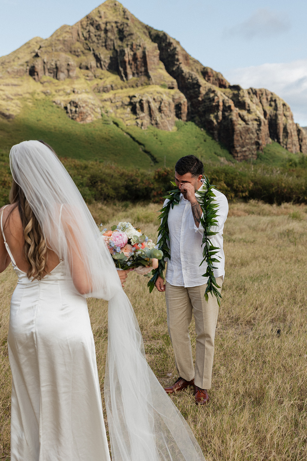 Groom wiping away tears during an emotional first look with his bride on their beach elopement day.