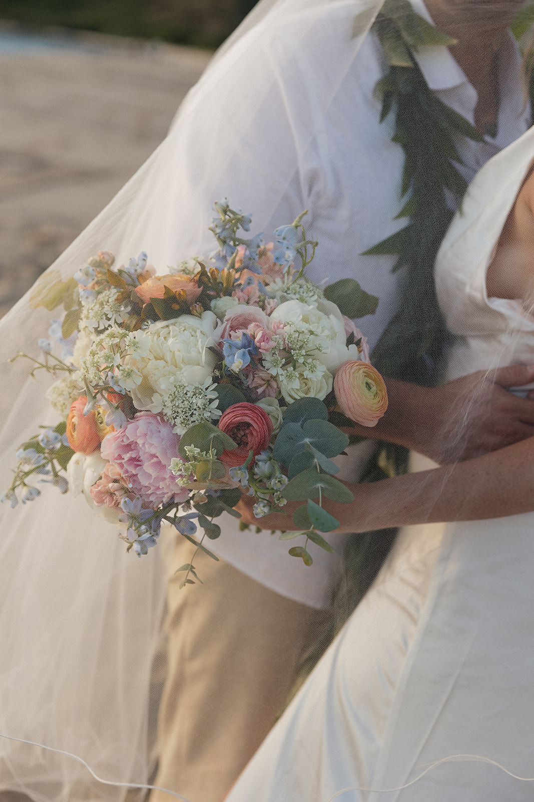 Close-up of the bride's colorful bouquet peeking through her veil.