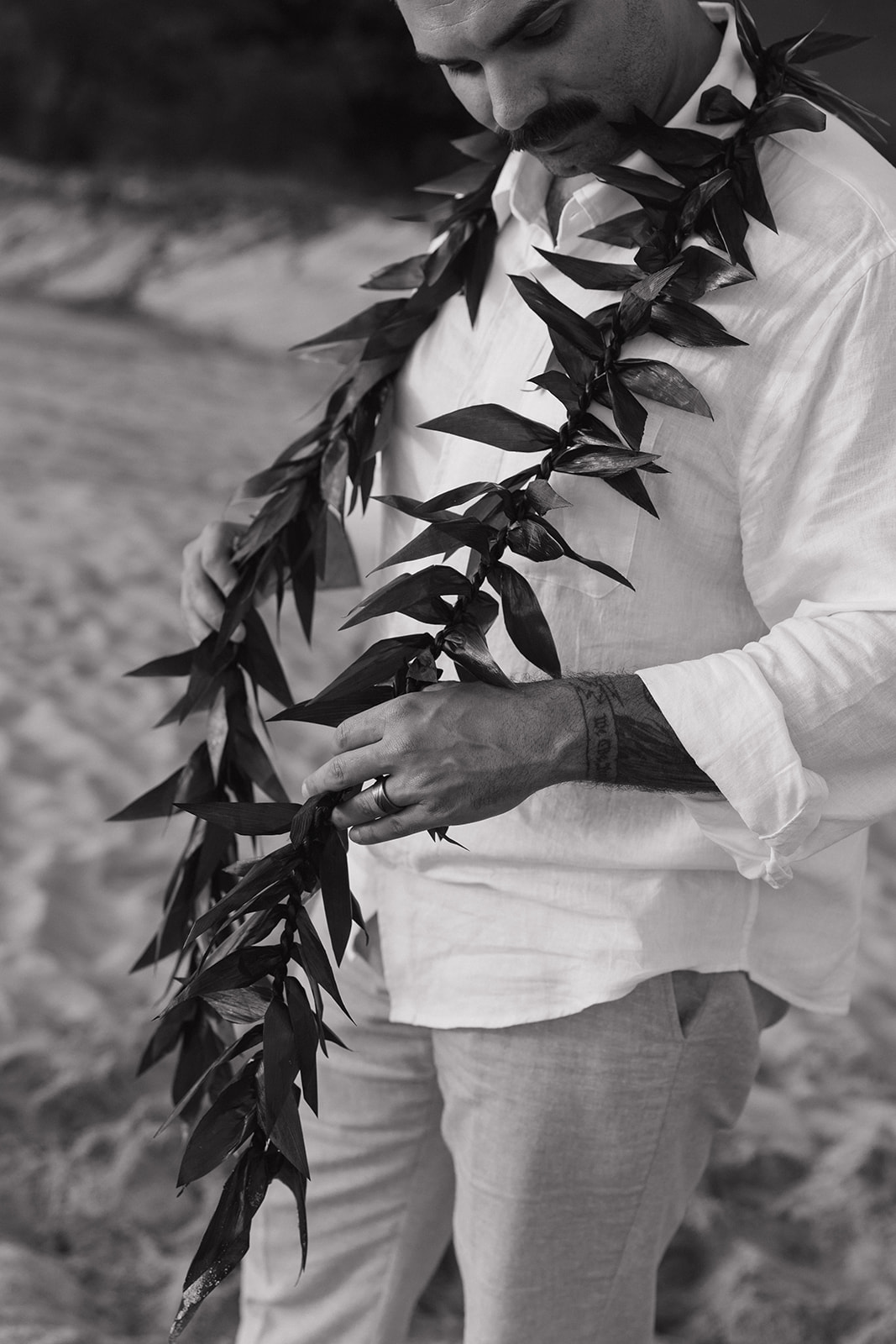 Black and white close-up of the groom's lei against his white shirt.