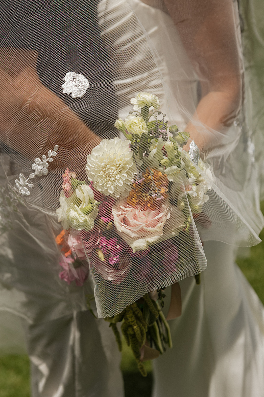 Sheer veil drapes over the bride's colorful bouquet in a soft, dreamy detail shot at this Maui wedding venue.