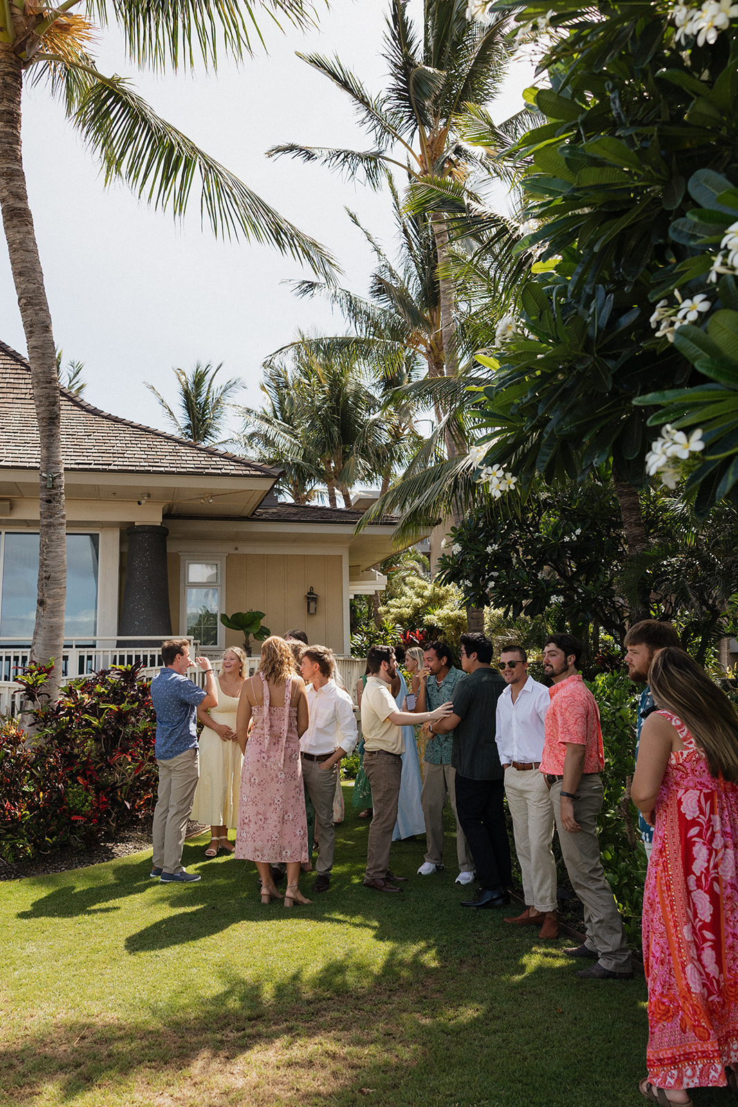Wedding guests gather and chat together on the lawn near the reception building before cocktail hour begins.