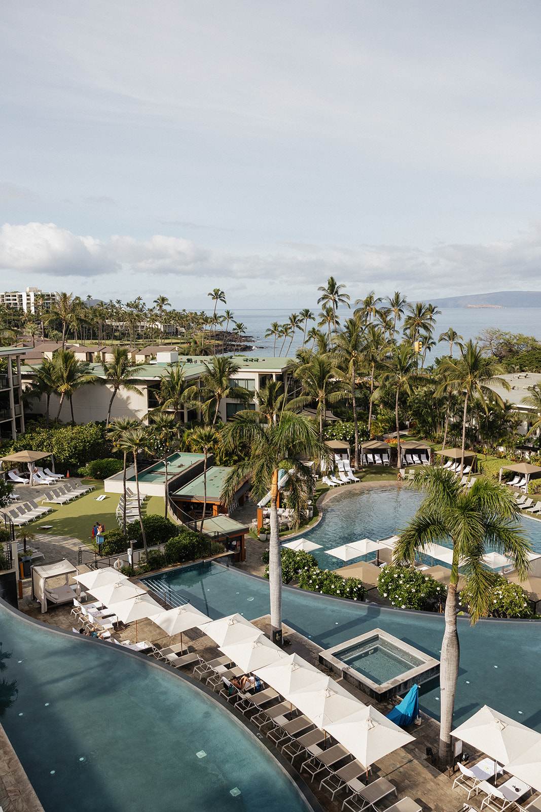 Aerial view of the resort's infinity pools, palm trees and turquoise coastline surrounding the wedding venue.