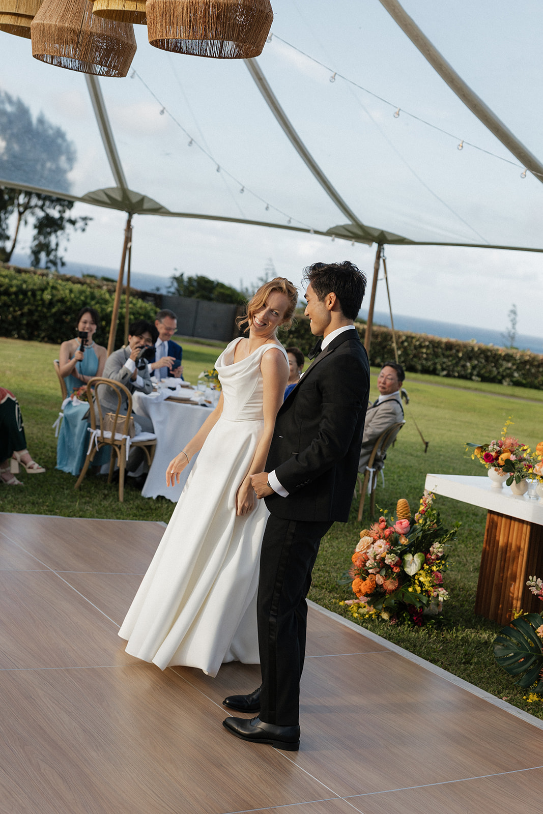 Bride laughing and glancing back at her groom during their first dance at the Maui Pineapple Chapel reception.