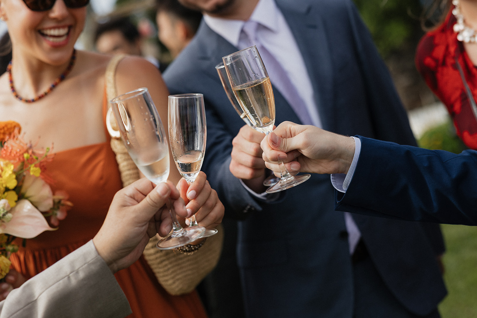 Wedding guests clinking champagne flutes in a celebratory toast outside the Maui Pineapple Chapel.