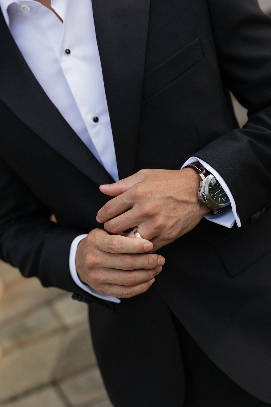 Close up of a groom in a black tuxedo with a classic wristwatch adjusting his wedding band before his Maui Pineapple Chapel ceremony.